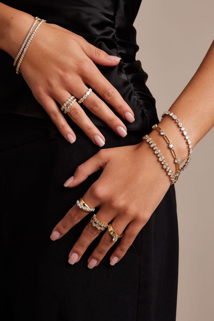Hands wearing stacked gold and diamond rings and bracelets